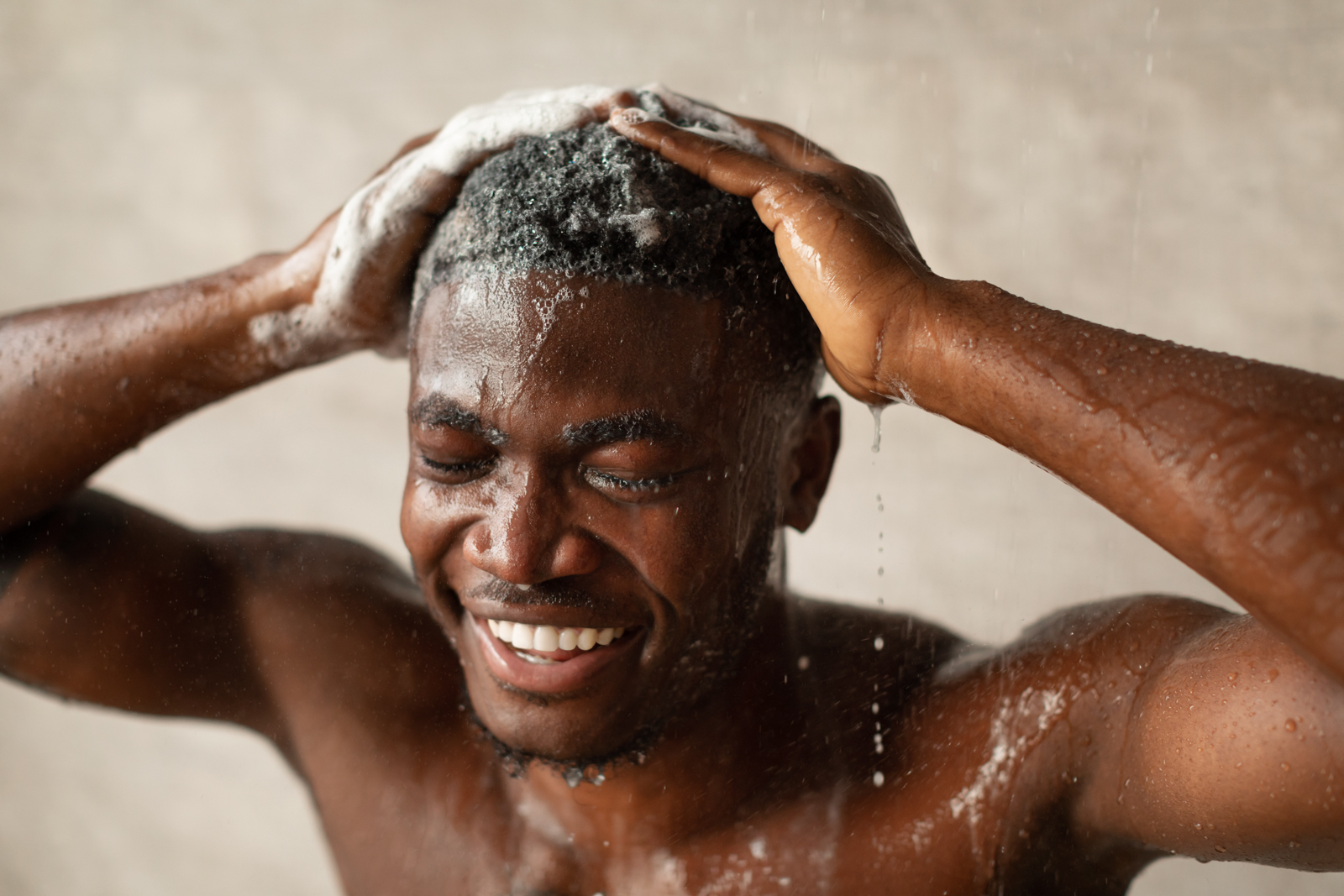 Man in shower uses a hair care product