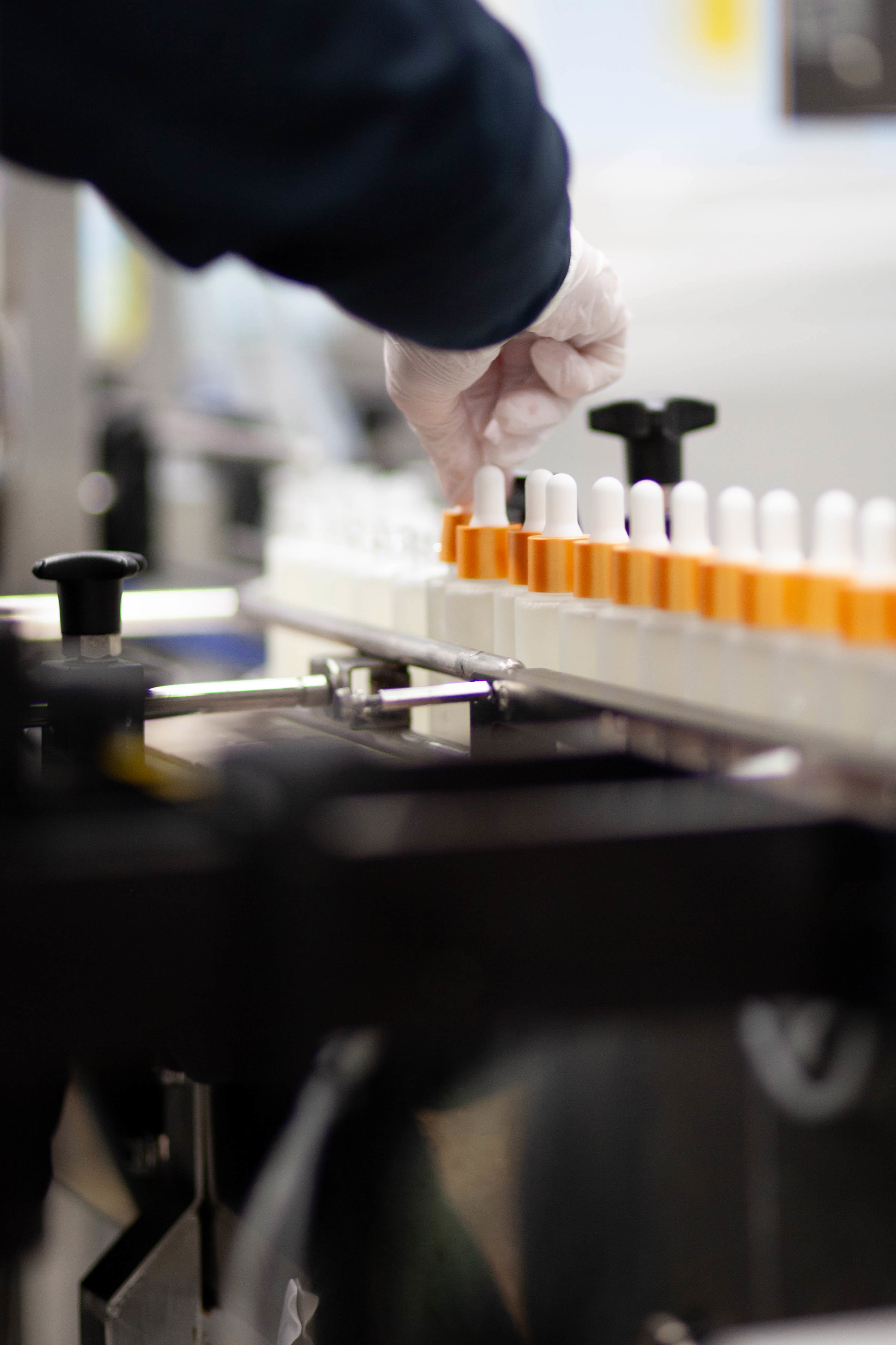 Person with plastic glove screwing on dropper top