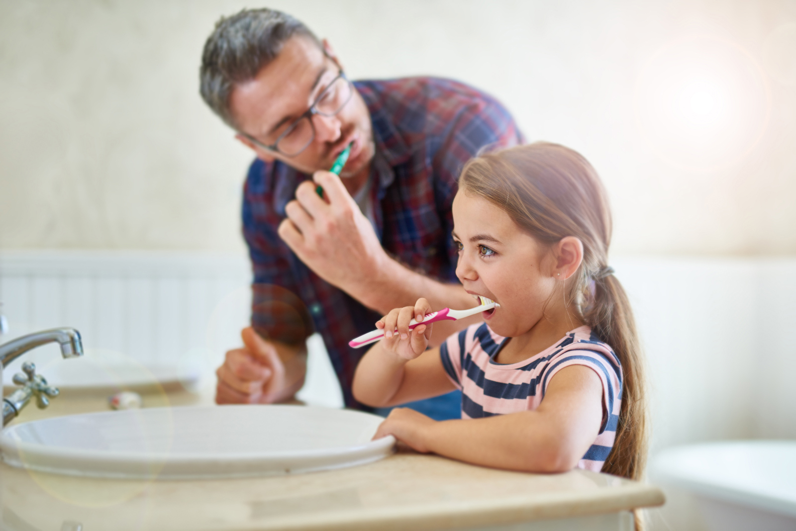Man and girl brushing their teeth