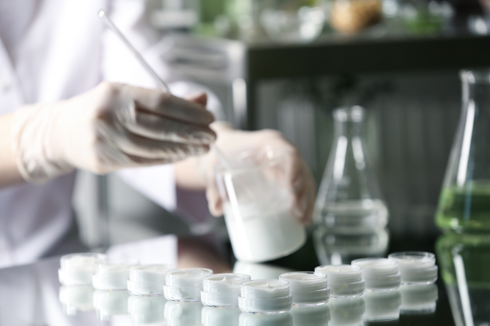 Person in a laboratory testing and handling product formulations in containers