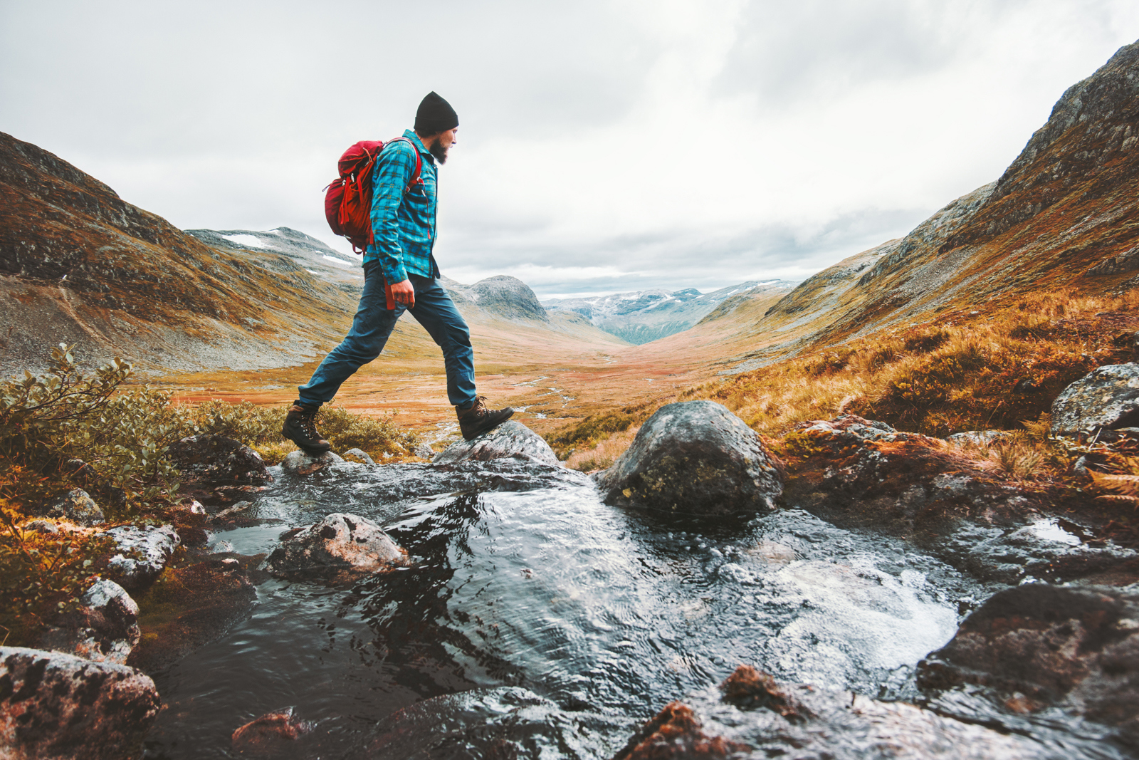 Person hiking through a mountain landscape while crossing a stream